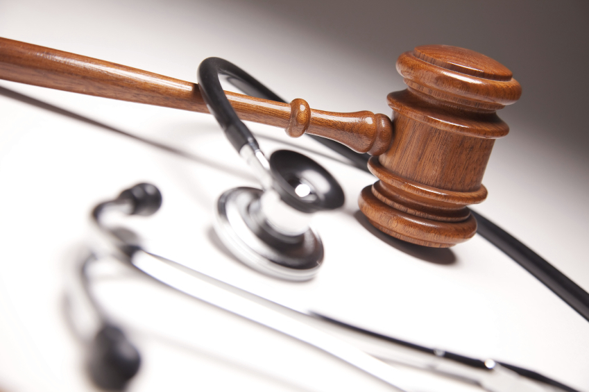 Wooden judge's gavel resting on a black stethoscope, symbolizing medical law or healthcare litigation