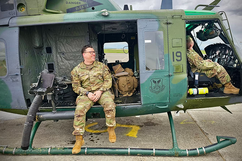 MIchigan Air National Guard serviceman sitting on side of open helicopter door.