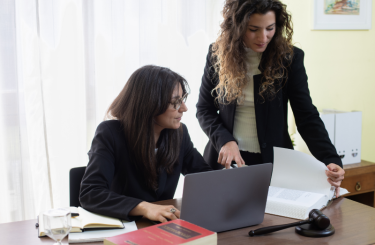 Two lawyers discussing documents at desk.