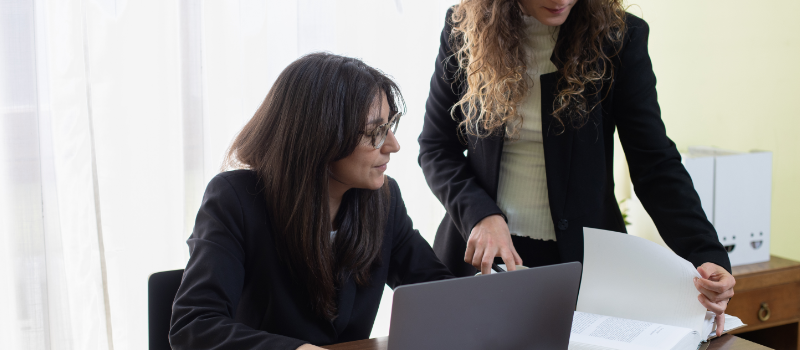 Two lawyers discussing documents at desk.