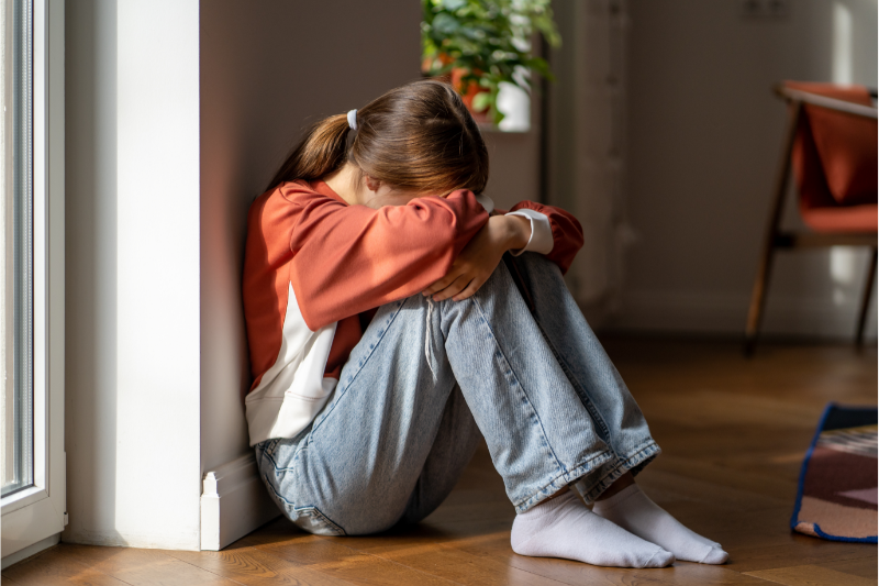 Upset teenage girl sitting on the floor