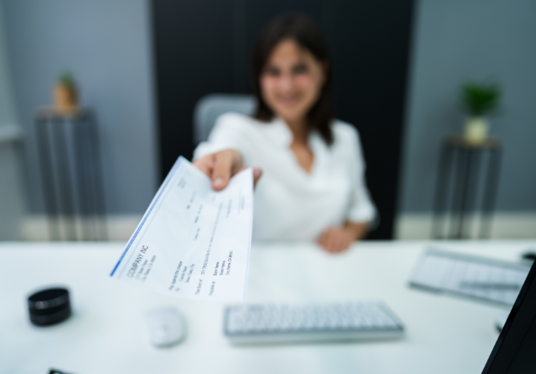 Female boss handing paycheck to employee