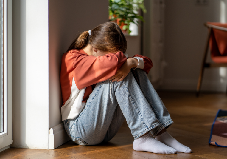Upset teenage girl sitting on the floor